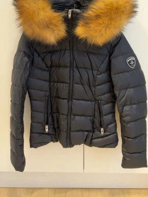Svart Rockandblue jacka med päls - Säljer en svart pufferjacka från Rockandblue i storlek 38, nästan helt oanvänd. Jackan har dragkedja framtill, två fickor med dragkedja och Rockandblue-logga på ärmen. Perfekt för kalla dagar och riktigt snygg siluett.