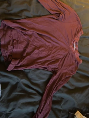 Vinröd långärmad topp med spets - Säljer en vinröd långärmad topp från XOXO friends. Toppen har en snygg spetskant vid halsringningen som ger en extra detalj. Materialet känns mjukt och stretchigt, perfekt till många olika looks.
