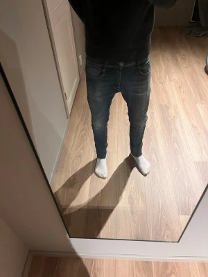 Mörkblåa slim fit jeans från Replay  - Säljer ett par mörkblå Replay jeans  med snygga slitningar!