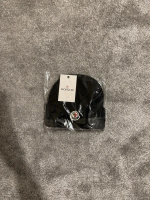 Moncler mössa - Hej, Säljer en svart ribbstickad mössa från Moncler. Den är helt oanvänd. Fick den som present men har redan en mössa så den kommer tyvärr gå till salu. Hör gärna av er vid frågor. 
