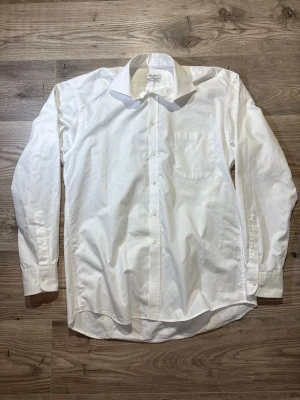 Stenströms - Klassisk vit skjorta från Stenströms i storlek 40. Tillverkad i exklusiv twofold super cotton för en mjuk och lyxig känsla. Skjortan har lång ärm, bröstficka och knappar framtill. Perfekt för dig som gillar stilrena och tidlösa plagg.