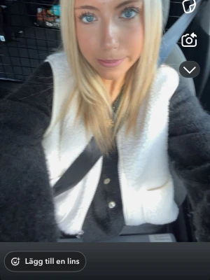 Vit teddyväst i storlek XS - Mysig vit teddyväst med två stora fickor framtill och dragkedja. Västen har en enkel, rak passform och är gjord i ett fluffigt syntetmaterial som ger en cool och avslappnad look. Perfekt att slänga över en hoodie eller tröja för extra värme.💞