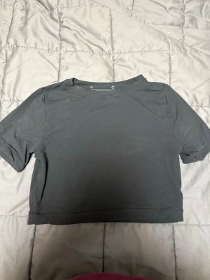 Svart croppad topp i polyamid - Säljer en enkel och stilren svart croppad topp från Cubus i storlek M. Toppen har korta ärmar och är gjord i ett stretchigt material med 76% polyamid och 24% elastan. 