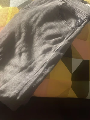 Grå Replay jeans - Säljer ett par grå jeans från Replay med klassisk femficksdesign och diskret Replay-logga vid fickan. Jeansen har rak passform och är tillverkade i ett slitstarkt jeanstyg som passar perfekt till vardagslooken. Storlek 12 A wallys. Mycket bra skick! Sparsamt använda och inte urtvättade 