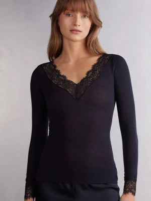 Svart spets intimissimi - Svart långärmad topp med djup v-ringning och fina spetsdetaljer längs halsringningen och vid ärmsluten. Toppens material är tunt och stretchigt, vilket ger en slim passform. Perfekt för dig som gillar en stilren look med en touch av spets. Säljer då jag ej använder den längre! Tröjan har små hål i sig så kom privat för de bild!!!