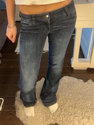 Mörkblå bootcut jeans med låg midja CHEAP MONDAY - Säljer ett par mörkblå jeans från cheap monday med bootcut passform och låg midja. Passar mig som har S. Har slitningar längst ner vid hälen annars bra skick.