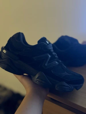 Svarta New Balance 9060 sneakers - Säljer ett par svarta New Balance 9060 sneakers i storlek 42. Skorna har chunky sula, mesh och mockadetaljer samt tydlig N-logga på sidan. Klassisk snörning och riktigt snygg streetstil. Perfekta för dig som gillar sportig och modern look.