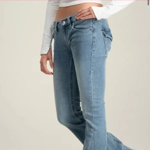 True religion jeans med låg midja och bootcut - Säljer ett par ljusblå jeans med bootcut-modell och låg midja. Jeansen har klassiska fem fickor och är tillverkade i mjukt denimtyg. Perfekta för dig som gillar en avslappnad och trendig look.