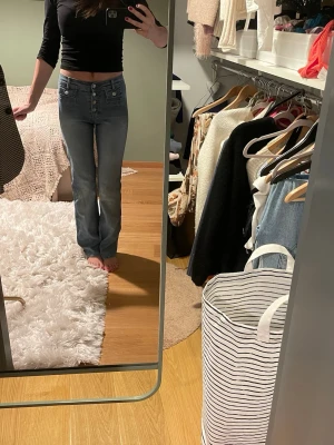 Blå jeans med medel hög midja och knappar - Vintage ljus blå jeans med mellan hög midja och flera  knappar framtill. Jeansen har raka ben och  broderade fickor.  