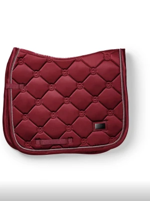 Equestrian Stockholm schabrak rött - Säljer ett vinrött schabrak med quiltat mönster och dekorativ kant i beige. Schabraket har praktiska remmar för fastsättning och är tillverkat i ett slitstarkt tyg. Perfekt för dig som vill ha en snygg detalj till hästutrustningen. Det är ett dressyr schabrak i storlek cob, det är använt fåtal gånger och är i mycket bra skick.