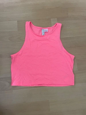 Neonrosa/korallfärgad croptop - Neonrosa/korallfärgad croptop från H&M i storlek s. Den är ca 37cm i längd så den är lite åt det kortare hållet. Fint skick, bara använts ett fåtal gånger.
