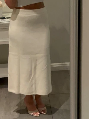 Vit lång kjol i bomull - Stilren vit lång kjol med rak passform och hög midja. Kjolen är enkel och minimalistisk, perfekt att matcha med crop tops eller stickade tröjor. Tillverkad i mjukt bomullstyg som ger en skön känsla och snyggt fall.