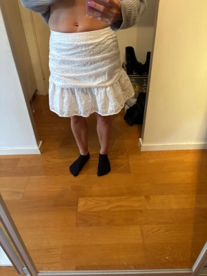Vit broderad volangkjol - Superfin vit kortkjol med broderade hål och volang nertill. Kjolen har en feminin och söt look med omlottkänsla och den är lätt och luftigt. Jag är lite osäker på storleken då jag har klippt bort lappen men den passar mig och jag har XS och S 😊
