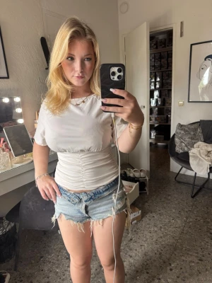 Ljusa jeansshorts med fransar - Säljer ett par ljusblå jeansshorts med råa, fransiga kanter och slitna detaljer. Shortsen har klassisk femficksdesign och normal passform. Perfekta för varma dagar och ger en avslappnad vibe. Flera knappar!