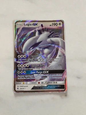 Lugia GX Pokémonkort - Säljer ett Lugia GX Pokémonkort med holografisk yta. Kortet har 190 HP och attacker som Psychic, Pelagic Blade och Lost Purge GX. Framsidan har en cool bild på Lugia och baksidan har klassiskt Pokémon-motiv.