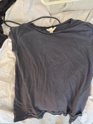 Mörkblå basic t-shirt - En enkel mörkblå t-shirt i mjukt bomullsmaterial. T-shirten har rund halsringning och korta ärmar, perfekt för en avslappnad och stilren look. Passformen är normal och tyget känns lätt mot huden.