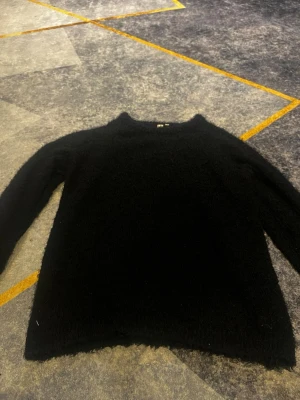 Svart fluffig stickad tröja DREAMS - Mysig svart stickad tröja från DREAMS i fluffigt material. Tröjan har rund halsringning och långa ärmar, perfekt för kyliga dagar. Enkel och stilren design som passar till det mesta.
