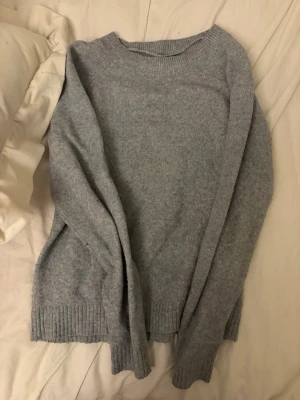 Ljusgrå stickad tröja Vero Moda - Mysig ljusgrå stickad tröja från Vero Moda i storlek XS. Tröjan har rund halsringning, långa ärmar och ribbade muddar vid ärmslut och nederkant. Perfekt för kyliga dagar och enkel att matcha till olika outfits.