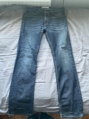 Mörkblå Levis jeans  - Säljer ett par mörkblå jeans med raka ben och snygga kontrastsömmar. Köpa second hand i Italien, därav är både Läderlappen där bak av, samt lapparna på insidan, men skulle gissa på att storleken är W33. Jeansen har klassisk femficksdesign och subtila slitningar framtill och baktill för en cool look. 