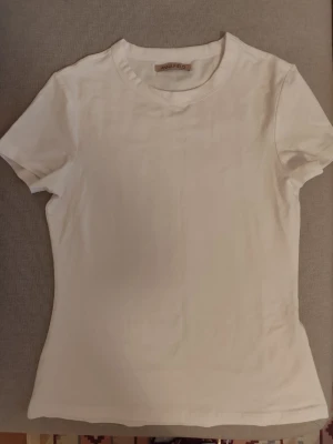Vit t-shirt från Anna Field - Klassisk vit t-shirt från Anna Field med rund halsringning och korta ärmar. Tillverkad i mjuk bomull som känns skön mot huden. Perfekt basplagg som passar till allt och är enkel att styla efter din egen smak.