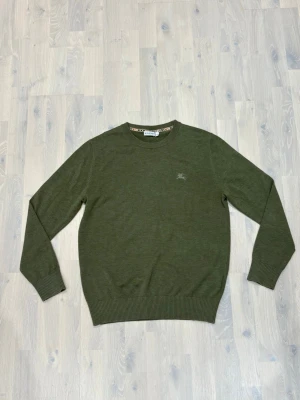 Olivgrön tröja Burrrbury - Snygg olivgrön tröja i mjuk stickad kvalitet. Rund halsringning med diskret -logga broderad på bröstet och ribbade muddar vid ärmslut och nederkant. Perfekt för dig som gillar klassisk och stilren design.