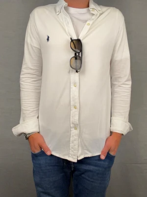 Ralph lauren skjorta S vit - Säljer denna fantastiskt snygga ralph lauren skjorta. Riktigt skönt material . Size S. Modellen är 180cm. Bredd 45cm längd 67cm! Fint skick, nytvättad och ny strykt så att skillnaden på denna och en ny ska vara minimal! Tyvärr är de ett litet hål där bak men de går att laga Fraktar samma dag som köp, kan gå ner i pris vid snabb affär! 🤩
