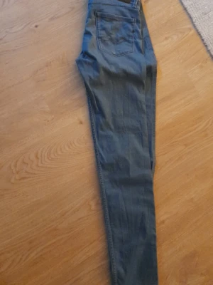 Replay Anbass jens - Snygga blå slim fit jeans från Replay, modell Anbass. Jeansen har klassisk femficksdesign och är tillverkade i stretchigt material för extra komfort. Perfekta för dig som gillar en smalare passform och stilren look. Str 29