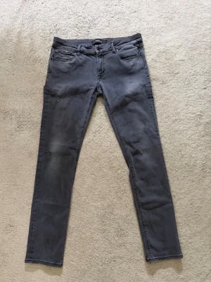 Grå Slim Fit Jeans – Replay | W31/32 -  Säljer ett par grå slim fit-jeans från Replay 🩶  👖 Storlek: M / W31–32 ✨ Slim fit med smala ben 🩶 Grå färg med diskreta slitningar 📌 5 fickor 👌 Mjukt och stretchigt material för bra komfort  Snygga och enkla jeans som passar till både vardag och en mer clean outfit.