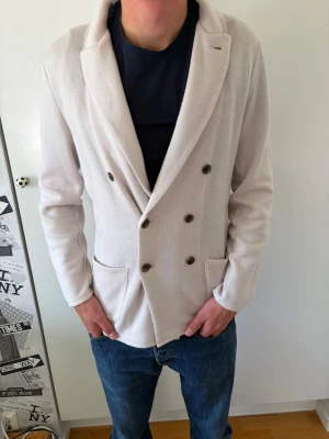 Beige dubbelknäppt blazer från John Henric  - Beigefärgad blazer från John Henric i 100% merinoull. Storlek L och i bra skick. Han på bilden är 187cm