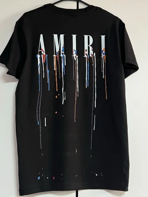 AMIRI T-shirt svart – Trendig design - Svart AMIRI T-shirt med snyggt tryck fram och bak. I mycket fint skick, använd endast ett fåtal gånger. Bekväm passform och perfekt till vardags eller streetwear.