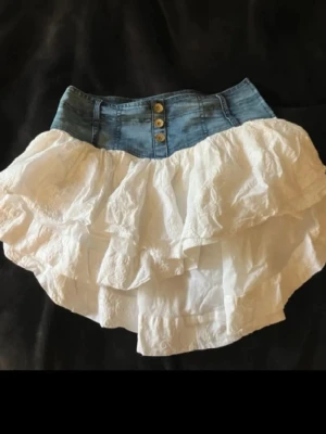 Vit volangkjol med jeansmidja från Phard - Supersöt kortkjol från Phard med jeansmidja och knappar framtill. Lite sådär Stockholmsstil och somrig 