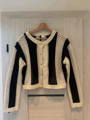 Svartvit Hålstorickad Kofta - Säljer denna ursnygga kortare kofta med en cool svartvit randig design. Den är hålstorickad (virkat utseende)  • Märke: H&M. • Storlek: S (EU 36). • Material: 100% akryl. • Passform: Lite lösare, kortare modell.   • 🏠 Jag säljer från ett rök- och djurfritt hem. • ⚡ Snabb leverans: Jag paketerar och skickar paketet inom 24 timmar efter köp!  