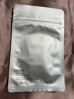 Rhode Spotwear pimple patches - Rhode Spotwear hydrocolloid pimple patches i en stilren, vit förpackning. Innehåller 36 plåster i blå, grå och orange färg. Perfekt för punktbehandling av finnar och orenheter. Enkel att ta med och använda när som helst.