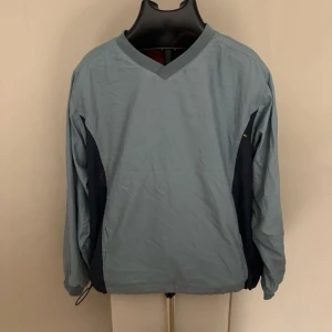 Quiksilver Blå och marin vindjacka med V-ringning - Snygg vindjacka i ljusblått och marinblått med V-ringad hals och elastisk nederkant. 0393