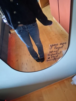 Blå bootcut jeans med fickdetaljer - Säljer ett par blå bootcut jeans med snygga fickdetaljer bak och knappar på fickorna. Jeansen har normal midja och klassisk femficksmodell. Perfekta för dig som gillar en avslappnad men trendig stil.