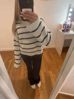 Vit stickad tröja med svarta ränder - Säljer en vit stickad tröja från Kappahl med svarta horisontella ränder. Tröjan har rund halsringning och en avslappnad passform. Perfekt för dig som gillar klassiska ränder och mjuka material.