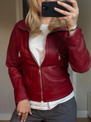 Röd skinnjacka från Auluna Leather Company - Snygg röd äkta skinnjacka från Auluna leather company i äkta skinn med dragkedja framtill och två dragkedjefickor. Otroligt fin röd färg, storlek S. Säljes pga för liten. 