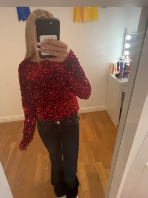 Röd paljettopp från Lindex - Glittrig röd topp från Lindex täckt med paljetter. Modellen har rund halsringning och långa ärmar. Perfekt för dig som vill sticka ut och glänsa lite extra. Toppens material känns mjukt mot huden och ger en snygg, festlig look.
