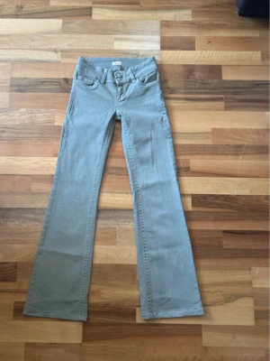 Grå bootcut jeans från Nelly - Snygga grå bootcut jeans från Nelly med dubbla knappar i midjan och klassiska fickor fram och bak. Jeansen har utsvängda ben och är tillverkade i ett mjukt bomullsmaterial med synliga sömmar. Perfekta för en trendig och avslappnad look.                                                  OBS! Upplagda för kroppar som är 160/162 cm långa!