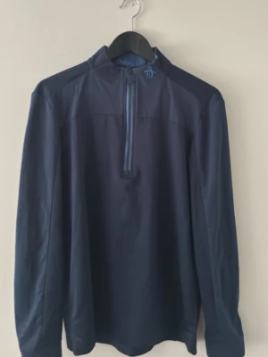 Mörkblå långärmad tröja med halv dragkedja - Snygg mörkblå långärmad tröja med halv dragkedja framtill och hög krage. Tröjan har en minimalistisk look och är tillverkad i ett slätt, sportigt material. Perfekt för dig som gillar stilrena plagg med en sportig touch.