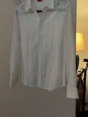 Vit klassisk skjorta med knappar - Stilren vit skjorta med lång ärm och klassisk krage. Skjortan har knäppning framtill och är tillverkad i ett lätt tyg som passar perfekt till många olika looks. Enkel och tidlös design som är lätt att matcha.