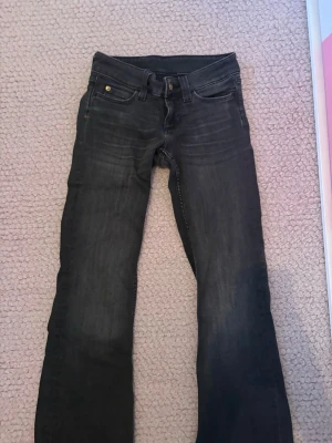 Svarta jeans från cheap monday - Säljer ett par svarta jeans med cool dödskalle på knappen. Jeansen har klassisk femficksmodell och utsvängda ben. Materialet är denim och färgen är tvättad svart med en avslappnad look. 