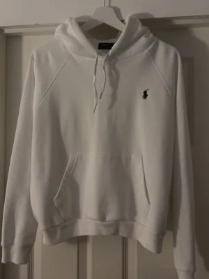 Vit hoodie från Polo Ralph Lauren - Snygg vit hoodie från Polo Ralph Lauren med klassisk broderad logga på bröstet. Hoodien har huva med dragsko, magficka och ribbade muddar vid ärmar och nederkant. Perfekt för en clean och stilren look. Strl L men passar mig som har s-m vanligtvis. Endast använd en gång💓nypris 2395kr