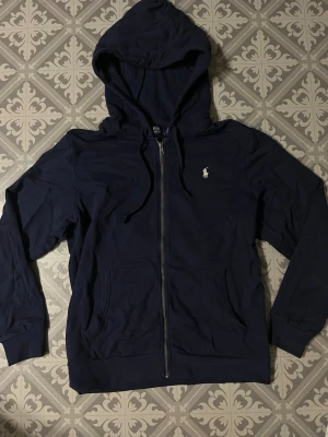 Mörkblå hoodie från Polo Ralph Lauren - Helt ny!!Mörkblå hoodie med dragkedja från Polo Ralph Lauren. Den är stor i storleken.