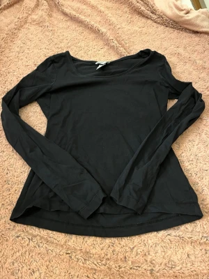 Svart långärmad topp från H&M - En enkel och stilren svart långärmad topp från H&M i mjuk pima bomull. Modellen har rund halsringning och smal passform, perfekt att matcha med jeans eller kjol. Materialet känns skönt mot huden och toppen är lätt att styla.