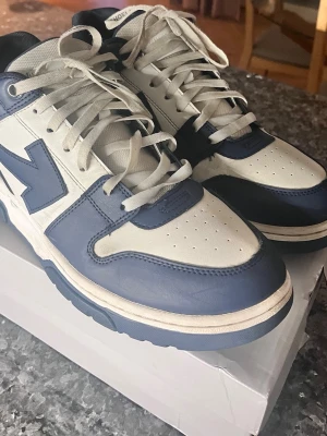Off White Out Of Office  - Snygga sneakers i blått och vitt med klassisk retrodesign. Skorna har perforerad tåbox, vita snören och en tydlig blå detalj på sidan. Ovandelen är i läder och sulan är vit med blå inslag. Passar perfekt för dig som gillar streetwear och sportig look. STORLEK 45. SKICKAS SAMMA DAG SOM KÖPES