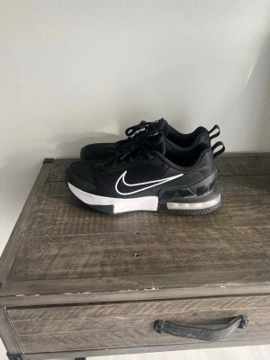 Nike Air Max svarta sneakers - Säljer ett par svarta Nike Air Max sneakers med vit sula och tydlig Air Max-dämpning i hälen. Skorna har mesh-ovandel för bra ventilation, klassisk vit swoosh på sidan och svarta skosnören. Perfekta för dig som gillar sportig och stilren look.