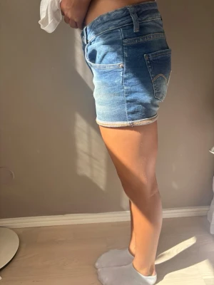Blå jeansshorts - Snygga blå jeansshorts med normal midja och klassiska fem fickor. Shortsen har uppvikta benslut och kontrastsömmar. Perfekta för sommaren och ger en avslappnad look. Tillverkade i denim med en lätt tvättad finish. Passar en 14 åring bra