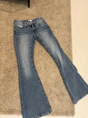 Blå bootcut jeans med slitningar - Säljer ett par oanvända ljusblå bootcut jeans från Gina tricot. Beställde de online och det blev fel storlek därför säljer jag dom.