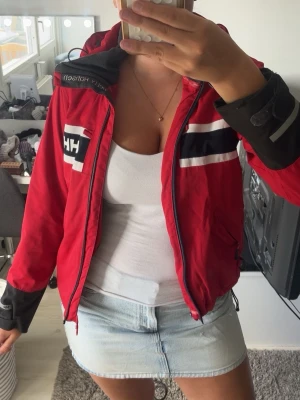 Helly Hansen jacka - Röd helly Hansen jacka, finns ett hål i nacken (syns inte lika mycket bakifrån). Fläckar som förmodligen går bort i tvätten, se bild. Finns ingen dragkedja.